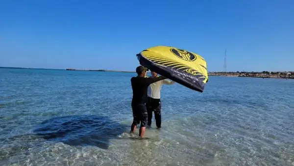 Instructor and student launching a kite in the water