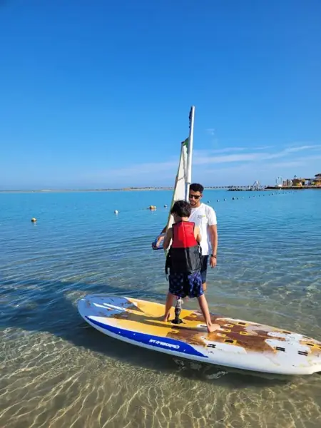 Instructor helping a boy on a windsurf board