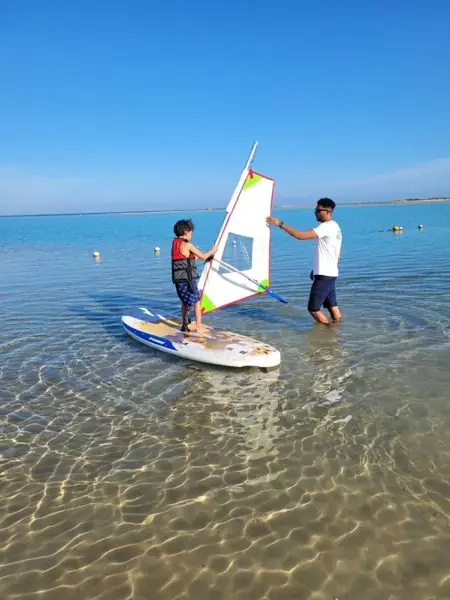 Instructor teaching a boy to windsurf