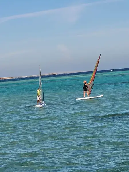 Two guests windsurfing on turquoise water
