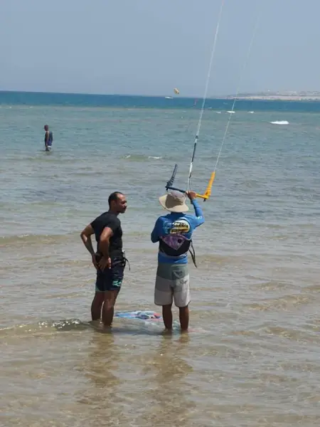 Instructor and student in shallow water with a kite bar