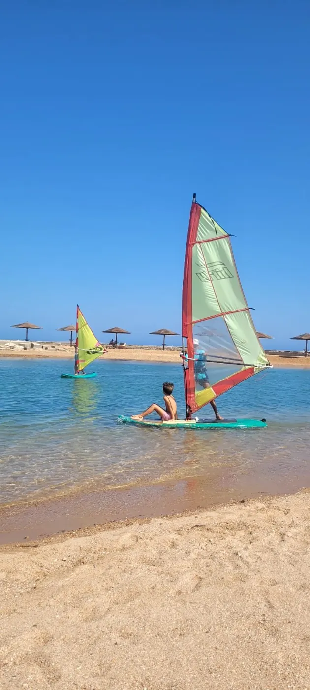 Two windsurf sails and a boy sitting on the board