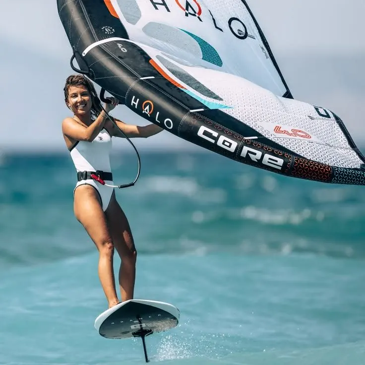 Woman wing foiling above the water